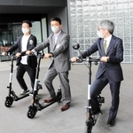 共同会見で電動キックボードをお披露目する各団体の代表者たち＝豊岡市山王町