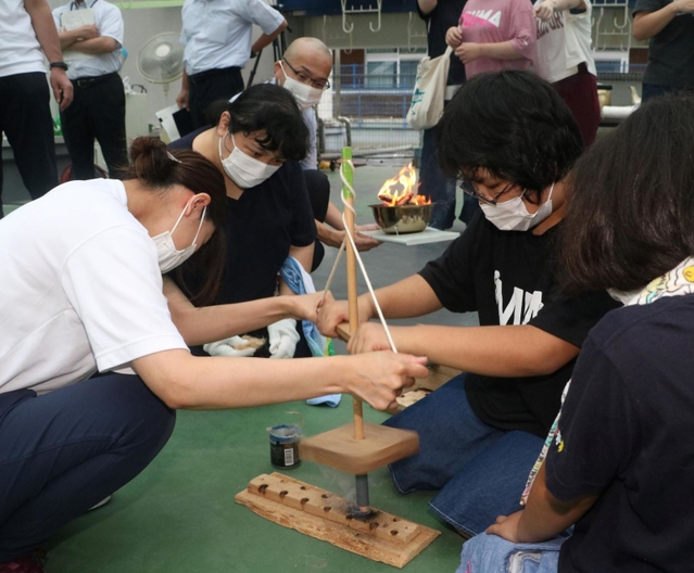 採火式で懸命に火をおこす児童生徒や保護者たち＝和田山特別支援学校