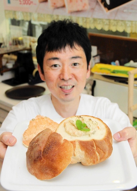 旅館に併設したカフェで提供する「香住かにクラムチャウダー」を手にする福田正幸さん＝香美町香住区七日市