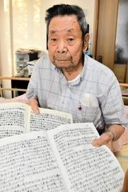 記録をしたためたノートを手にする藤本治憲さん＝豊岡市下陰