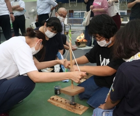 採火式で懸命に火をおこす児童生徒や保護者たち＝和田山特別支援学校