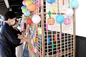 豊岡杞柳細工の職人が作った格子に願い事の短冊を飾るスタッフら＝豊岡市出石町内町