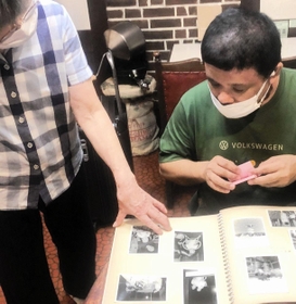 聞き取り取材をする脚本指導・演出担当のごまのはえさん＝ヒグラシ珈琲（毛帽子事務所提供）