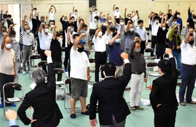 「頑張ろう」の声に合わせて拳を突き上げる住民ら＝城崎小