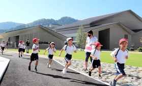 新文化会館「やぶ市民交流広場」の周辺を走る八鹿小の児童たち＝養父市八鹿町八鹿