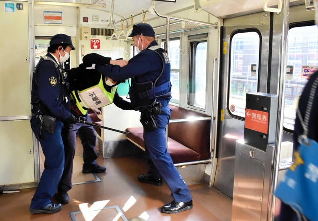 車両内で暴れる不審者役に対応する豊岡署員ら＝ＪＲ豊岡駅