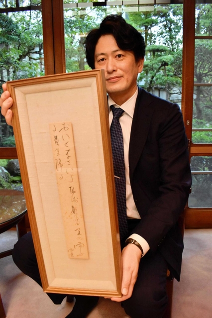 野口雨情がしたためた短冊を手にする西村総一郎社長＝西村屋
