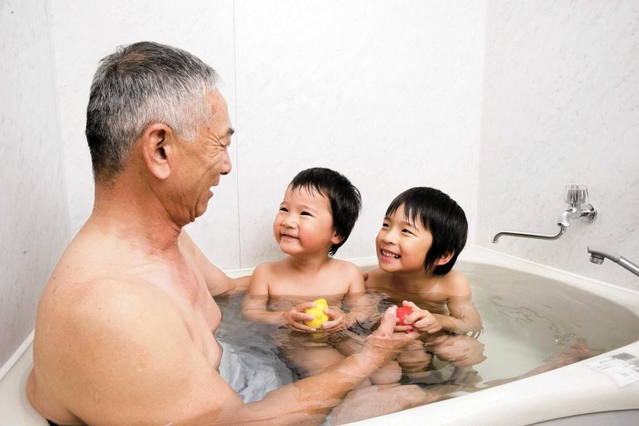 蛇口をひねれば天然温泉が出る家庭の風呂を楽しむ家族（同町提供）