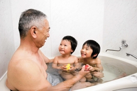 蛇口をひねれば天然温泉が出る家庭の風呂を楽しむ家族（同町提供）