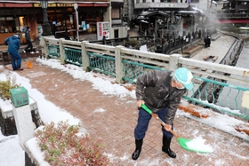 温泉橋に積もった雪をかく住民＝新温泉町湯