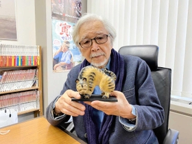 木彫フォークアートへの思いを語る山田洋次監督。養父市大屋町在住の作家、松田一戯さんが贈ったえとの置物を手にする（養父市提供）