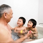 蛇口をひねれば天然温泉が出る家庭の風呂を楽しむ家族（同町提供）
