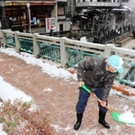 温泉橋に積もった雪をかく住民＝新温泉町湯