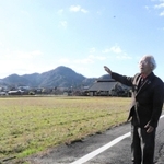 浜坂温泉が初めて見つかった場所。「辺りは水田が広がり、泥の層が温泉の湧出を妨げていた」と説明する谷本勇さん＝新温泉町浜坂