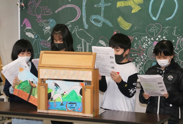 交通事故で死んだコウノトリ「翼」を主人公にした紙芝居を披露する４年生の児童たち＝東河小