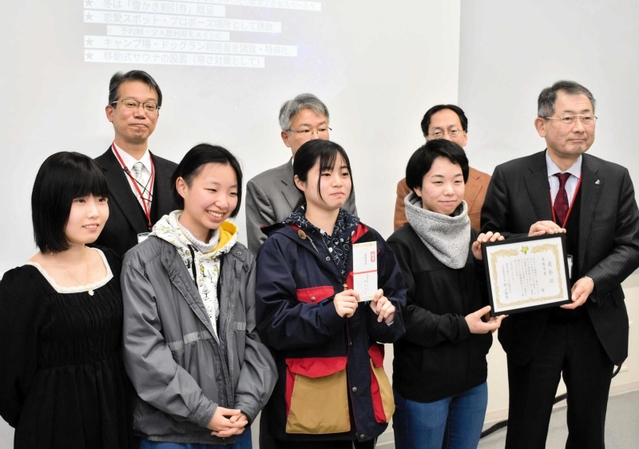 但馬空港ターミナルの桐山徹郎社長（前列右端）から賞状を受け取る最優秀賞受賞チームのメンバー＝芸術文化観光専門職大学