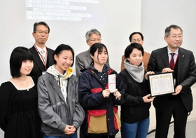 但馬空港ターミナルの桐山徹郎社長（前列右端）から賞状を受け取る最優秀賞受賞チームのメンバー＝芸術文化観光専門職大学