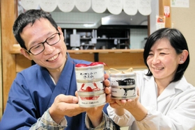 香住ガニと但馬牛、ノドグロを使った缶詰「香美缶」の３点セットと２点セットをＰＲする石田裕二さん（左）と佐也子さん＝香美町香住区香住