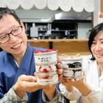香住ガニと但馬牛、ノドグロを使った缶詰「香美缶」の３点セットと２点セットをＰＲする石田裕二さん（左）と佐也子さん＝香美町香住区香住