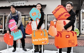 かばんをたくさん持っているように見えるパネル＝豊岡市中央町