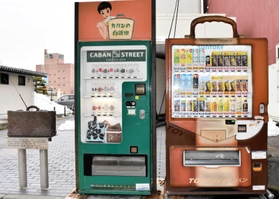 カバンをモチーフにした自販機（右）と手提げかばんが出てくる「カバンの自販機」、モニュメント＝豊岡市中央町