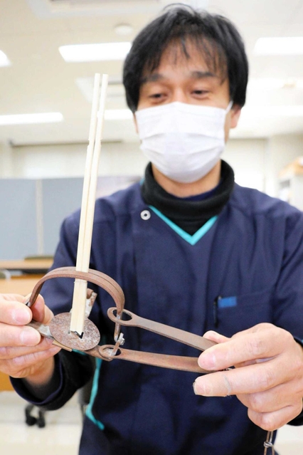 コウノトリが負傷した同型のとらばさみに割り箸をはさみ再現する松本令以さん＝コウノトリの郷公園