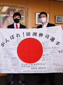 応援メッセージ入りの国旗を手にする田渕伸司選手（左）と関貫久仁郎市長（豊岡市提供）