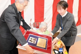 百寿を迎えた秋山幸枝さん（中央）に記念品を贈る西村銀三町長（左）＝新温泉町湯