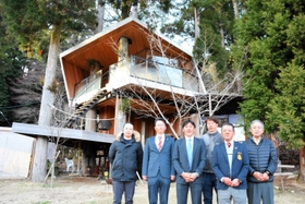 地方創生賞を受け、喜ぶ関係者たち。背後は５本のスギの間に造られたツリーハウス＝朝来市生野町栃原