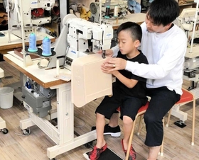 立体部分を父一樹さんに手伝ってもらう時も、ミシンの針を進めるのは翔君（坂井一樹さん提供）＝豊岡市出石町町分