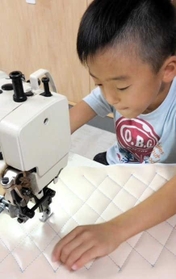 カバー部分のステッチを縫い上げる翔君（坂井一樹さん提供）＝豊岡市出石町町分