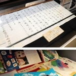 【上】久谷駅の開業を喜び、美方郡長が読んだ祝辞文【下】浜坂駅前で販売された駅弁の包装紙＝新温泉町浜坂