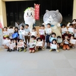 浜坂認定こども園の園児２１人と集合写真をとるマル（右）とハマダイコン＝加藤文太郎記念図書館