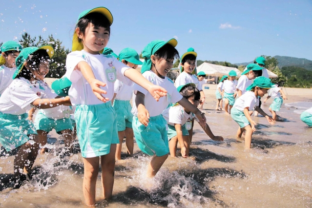 「冷たい！」。波打ち際で歓声を上げる園児＝香住浜海水浴場