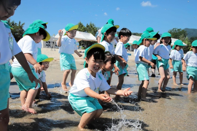 波打ち際で水遊びを楽しむ園児たち＝香住浜海水浴場