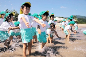 「冷たい！」。波打ち際で歓声を上げる園児＝香住浜海水浴場