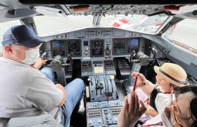 「ＡＴＲ４２－６００」の操縦席に座って体験する参加者たち。窓からは「ヤリスＷＲＣ」が見える＝但馬空港（撮影・岡本好太郎）