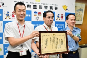 松本薫署長（右）から感謝状を受け取る土肥貞視さん（中央）と國眼聡局長＝豊岡署