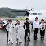 滑走路で飛行機とスポーツカーの前で記念撮影をする関係者ら＝但馬空港
