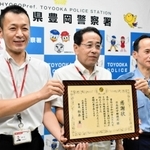 松本薫署長（右）から感謝状を受け取る土肥貞視さん（中央）と國眼聡局長＝豊岡署