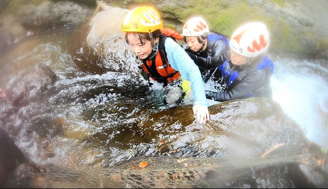 水流の激しい岩場をよじ登る女の子＝香美町小代区秋岡