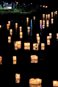 水面を照らしながら列をなす灯籠＝佐津川
