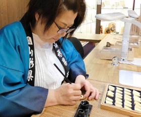 通常の木製の駒に文字入れをする天童市の職人（服部提供）
