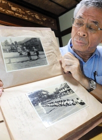 父忠雄さんが撮影した写真集を持つ川見章夫さん＝豊岡市出石町