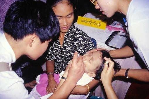 十分な医療が受けられないミャンマー貧困地区の幼児にポリオワクチンを投与する「懐」のメンバー（左）＝１９９８年１２月、ミャンマー国内