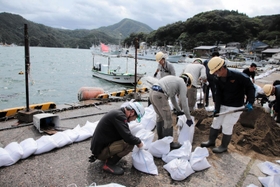土のうを作って岸壁沿いに並べる作業員ら＝香美町香住区沖浦