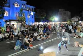 路上パフォーマンスやナイトマーケットでにぎわった豊岡市役所前＝豊岡市中央町