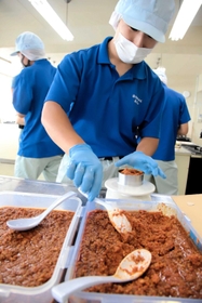 「中華料理　白龍」自慢の「旨辛肉」を缶詰にする生徒＝香住高校