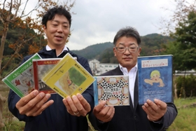 オリジナルＣＤを手にする作詞担当の久村謙藏さん（無駄信長、右）と、ギター兼ボーカルの勝地哲平さん（遊月亭いく藏）＝新温泉町井土