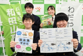 無料で配布する魚類図鑑と制作した生徒たち＝朝来市役所